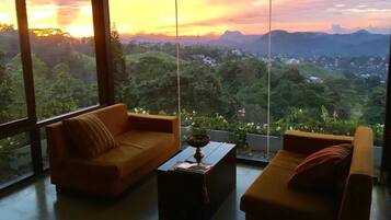 A room with two sofas facing a large window overlooking a lush landscape.