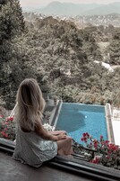 Una persona sentada junto a una piscina con vistas a un pueblo y colinas.