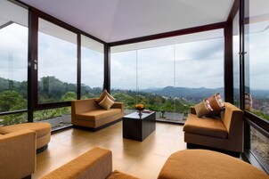 Una sala de estar moderna con ventanas amplias, un conjunto de sofás y una mesa de centro.