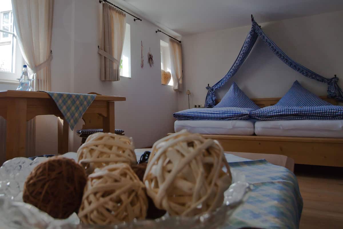A cozy room with a bed, a hammock, and a table with a checkered tablecloth.