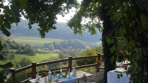 An outdoor dining area with tables set for a meal, overlooking a scenic landscape. - Landhaus Zum Falken (Adelshofen)