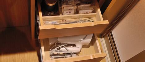 A drawer with various items including a white appliance, plastic bags, and a small container.