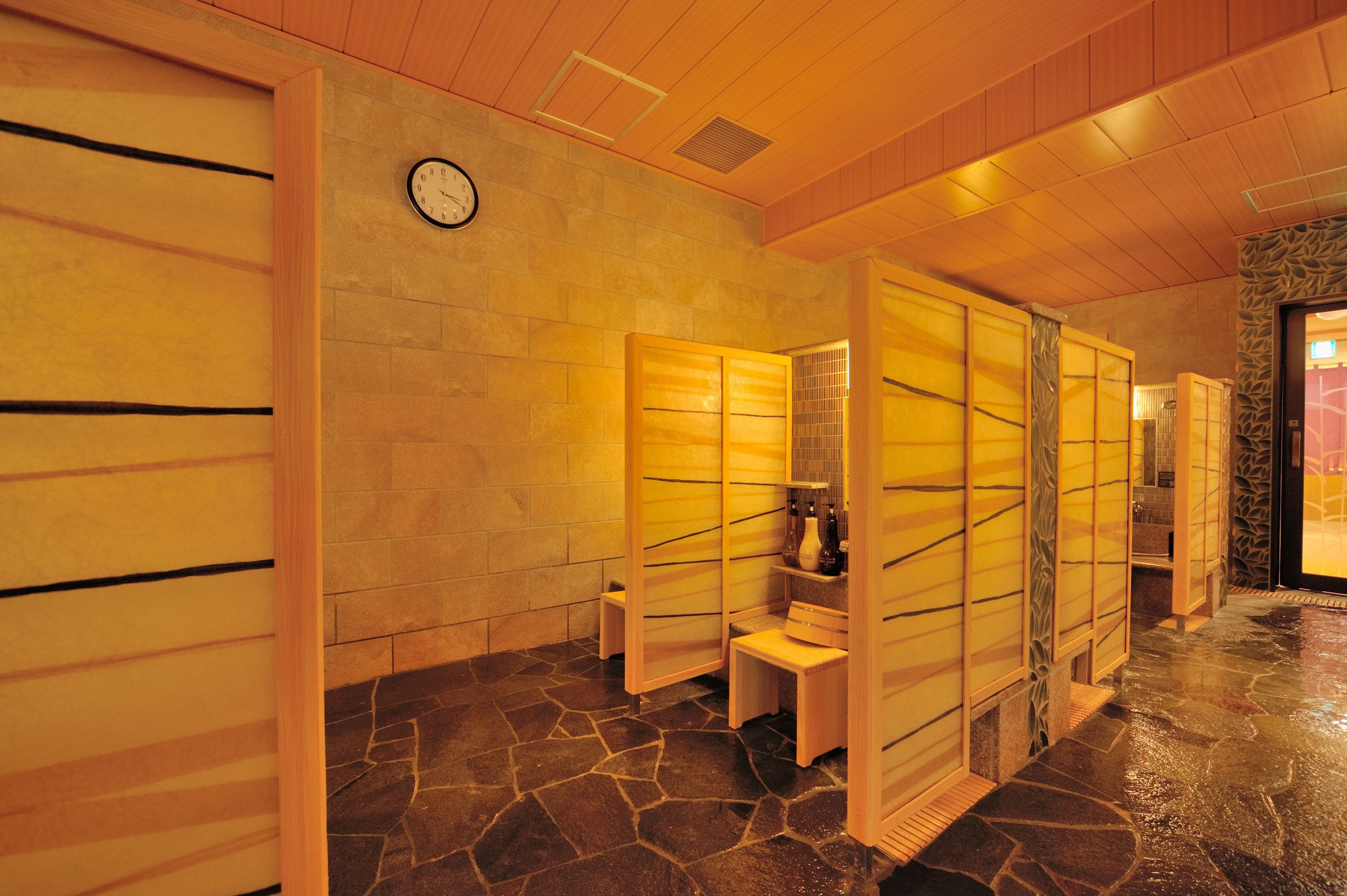 A traditional Japanese-style room with tatami flooring, sliding doors, and a stone wall.