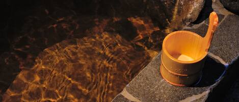 A wooden cup on a stone ledge by a clear water body.