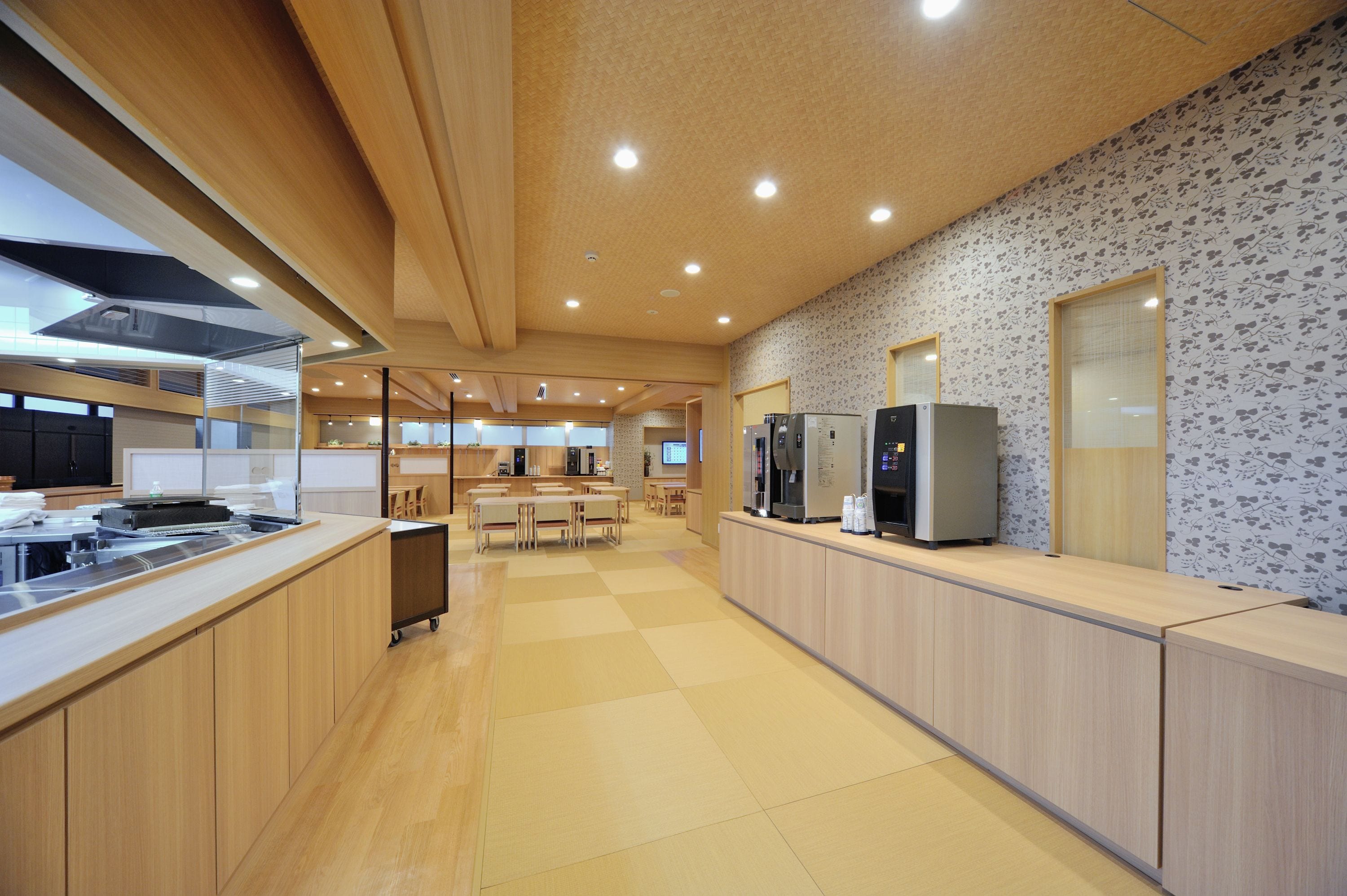 A modern kitchen with wooden cabinets, a central island, and a seating area with tables and chairs.