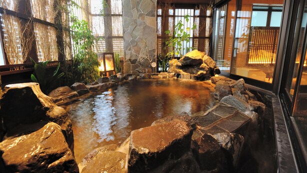 A hot spring area with a stone wall, wooden beams, and a small waterfall. - Tennen Onsen Toyama Tsurugi no Yu Onyado Nono (Toyama)