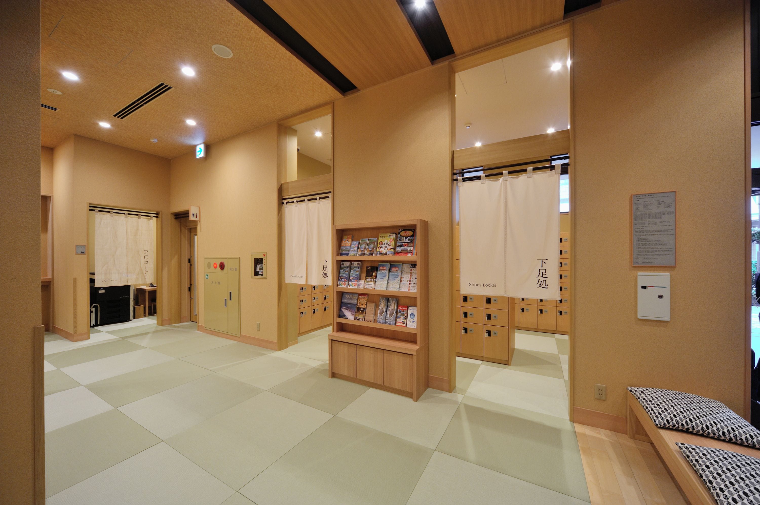 A hotel lobby with a checkered floor, wooden lockers, a reception desk, and a seating area.