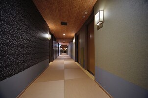 Un pasillo con una pared estampada a la izquierda, techo de madera y una lámpara a la derecha.