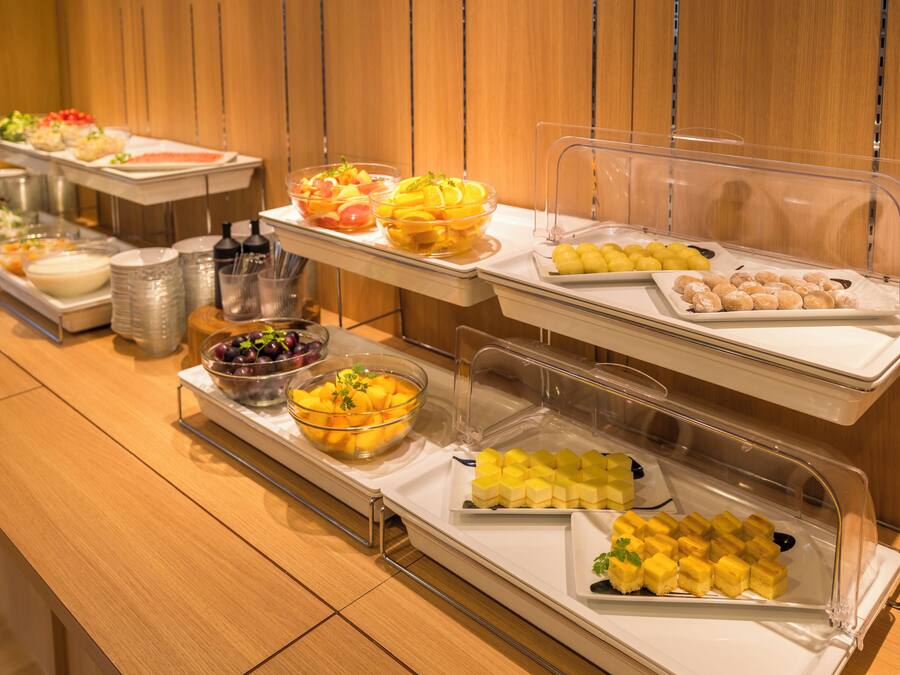 A buffet with various food items including fruits, vegetables, and pastries.