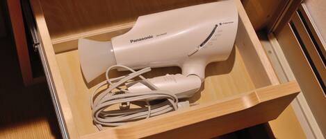 A drawer containing a Panasonic hair dryer with a cord.
