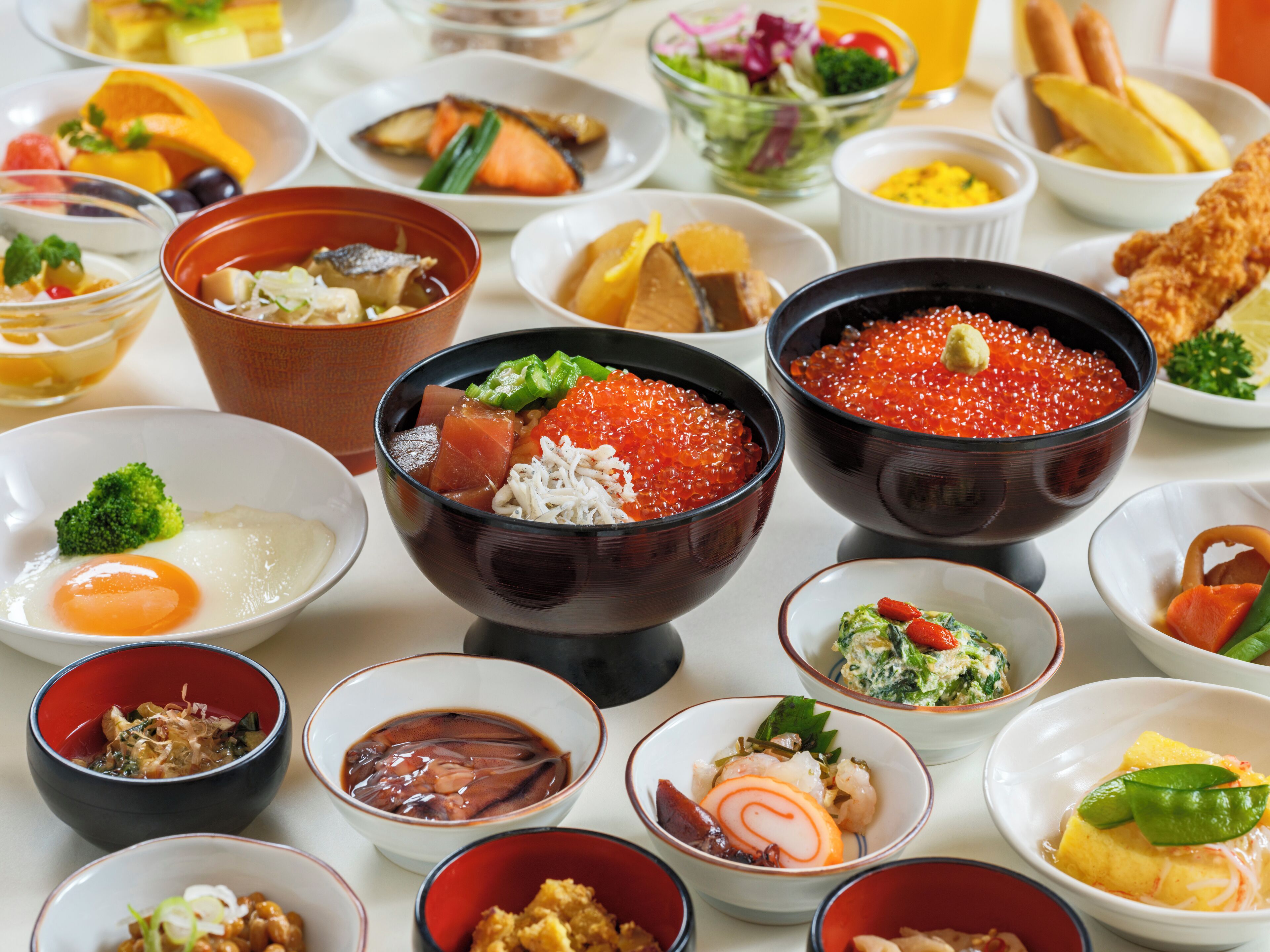 A variety of dishes including sushi, sashimi, and other Asian cuisine, arranged on a table.