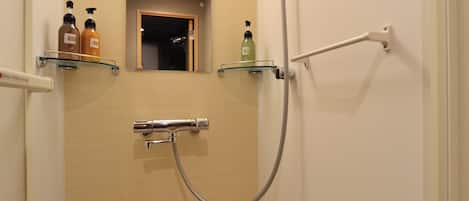 A small, narrow bathroom with a shower, a mirror, and two shelves with toiletries.