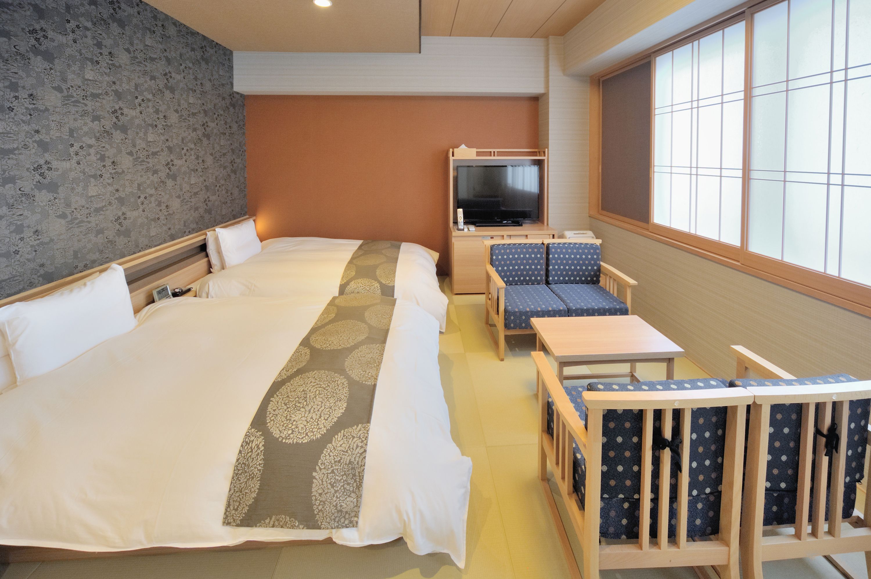 Een hotelkamer met een groot bed, een televisie, een tafeltje en twee stoelen.