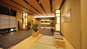 A modern interior with a wooden ceiling, tiled floor, and a reception area with seating and plants. - Tennen Onsen Toyama Tsurugi no Yu Onyado Nono (Toyama)