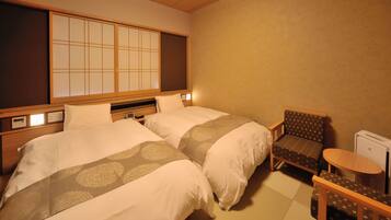 A hotel room with two beds, a traditional Japanese sliding door, a small table, and a chair.