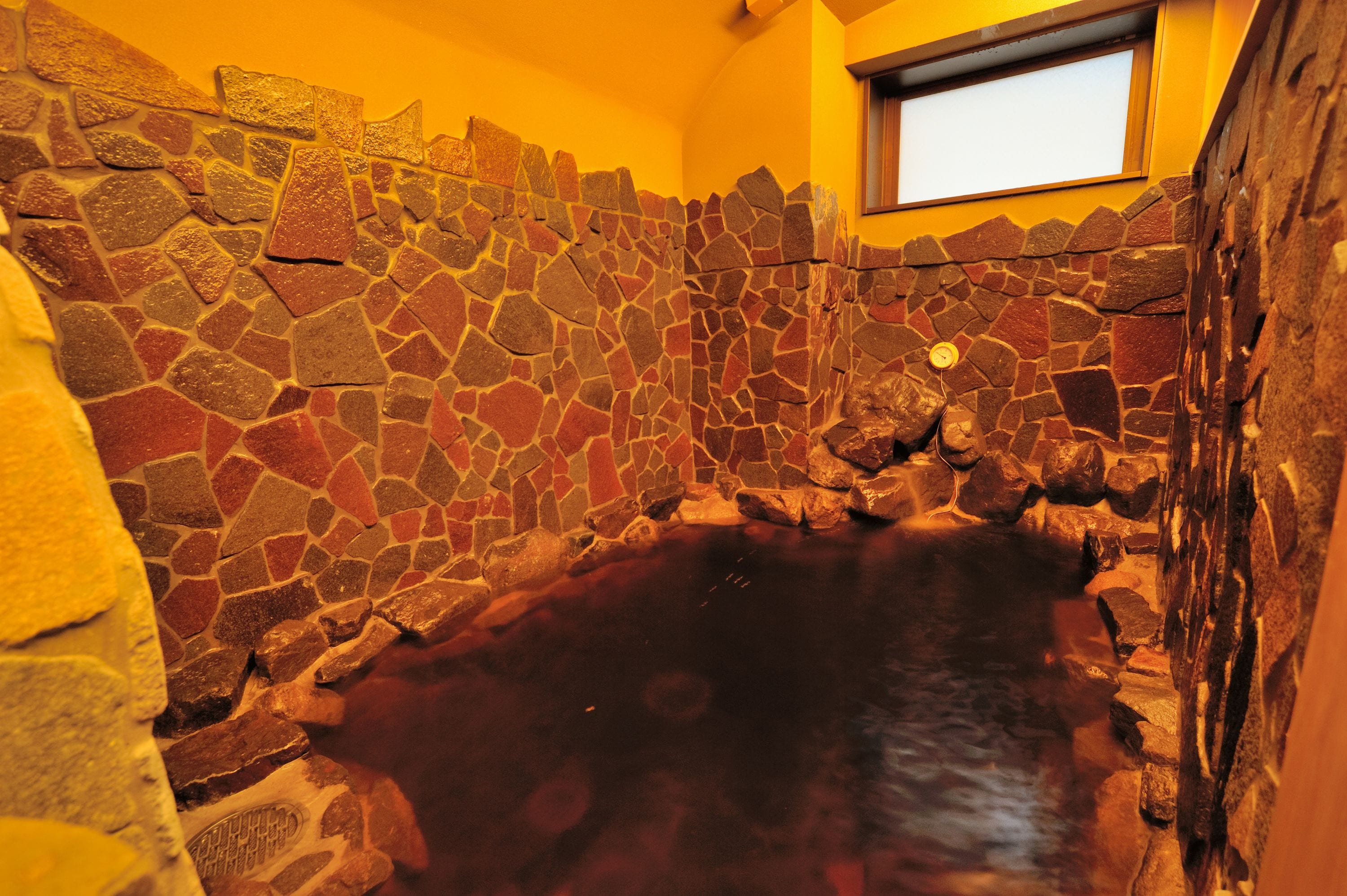 A stone-walled bathroom with a bathtub.