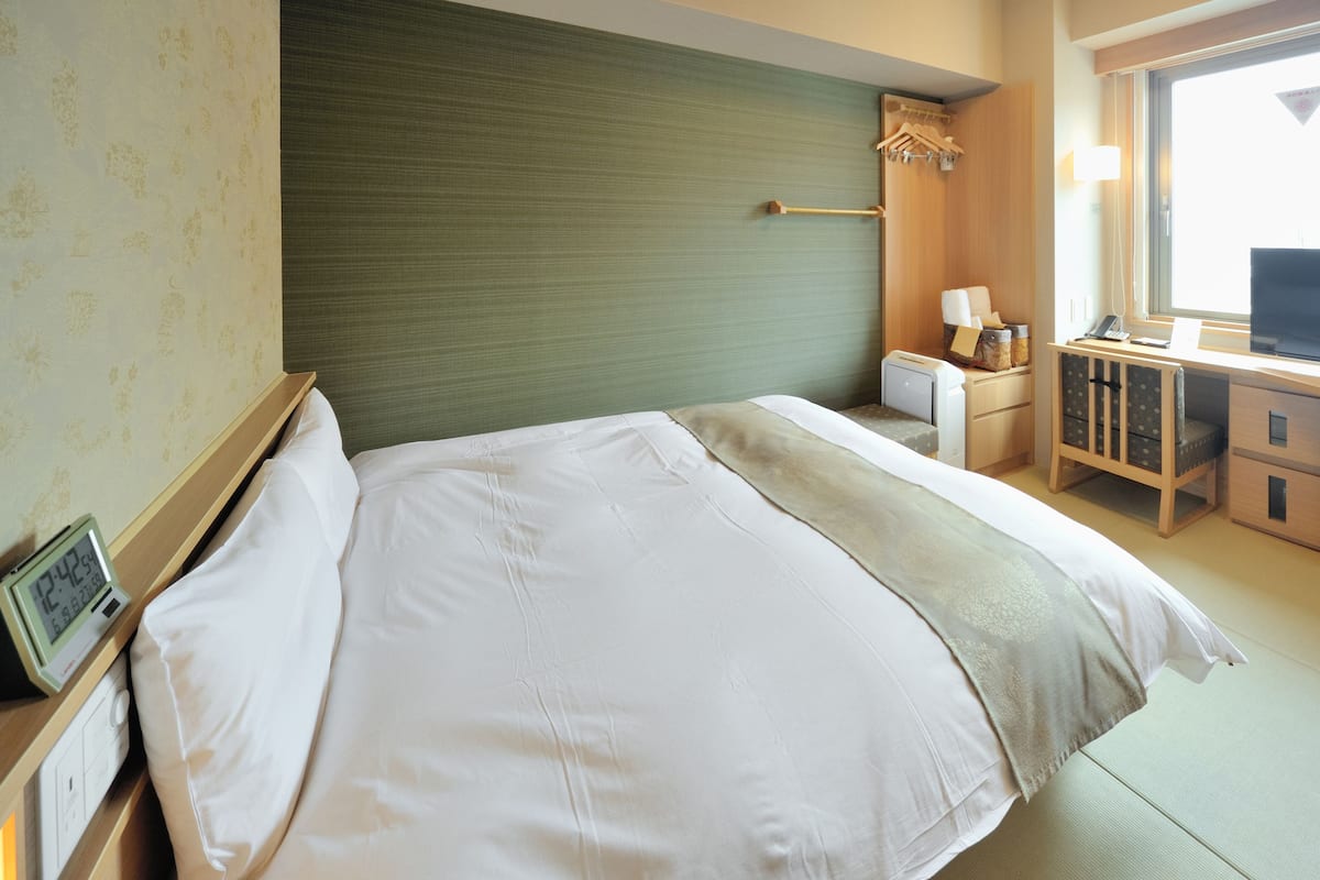 Una habitación de hotel con cama, mesita de noche, lámpara y escritorio con silla.