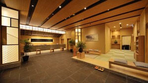A spacious lobby with a reception desk, seating area, and a checkered floor. - Tennen Onsen Toyama Tsurugi no Yu Onyado Nono (Toyama)
