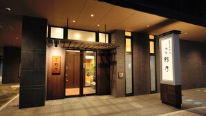 A hotel entrance with a wooden facade, a tiled entrance, and a signboard with text. - Tennen Onsen Toyama Tsurugi no Yu Onyado Nono (Toyama)