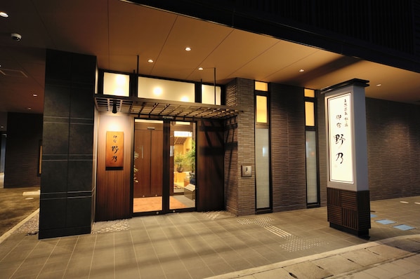 A hotel entrance with a wooden facade, a tiled entrance, and a signboard with text. - Tennen Onsen Toyama Tsurugi no Yu Onyado Nono (Toyama)