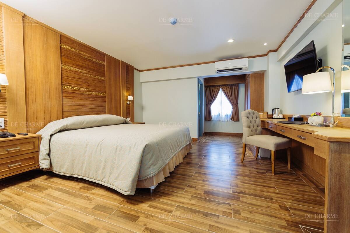 A hotel room with a bed, desk, chair, and a television.