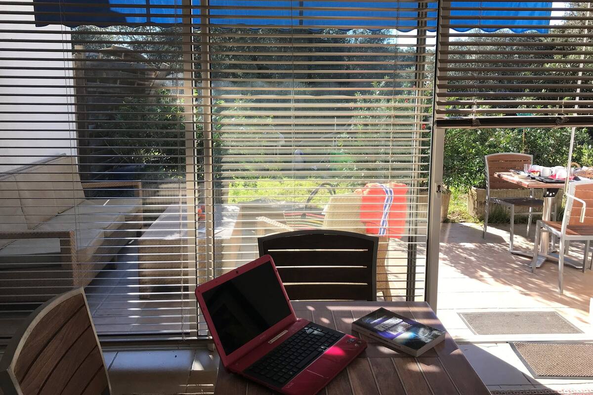 Eine Terrasse mit Tisch, Stühlen und einem Laptop.