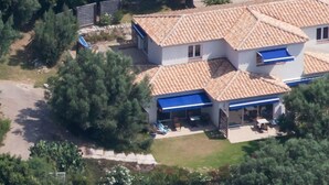 A two-story house with a tiled roof, a covered patio, and a driveway.