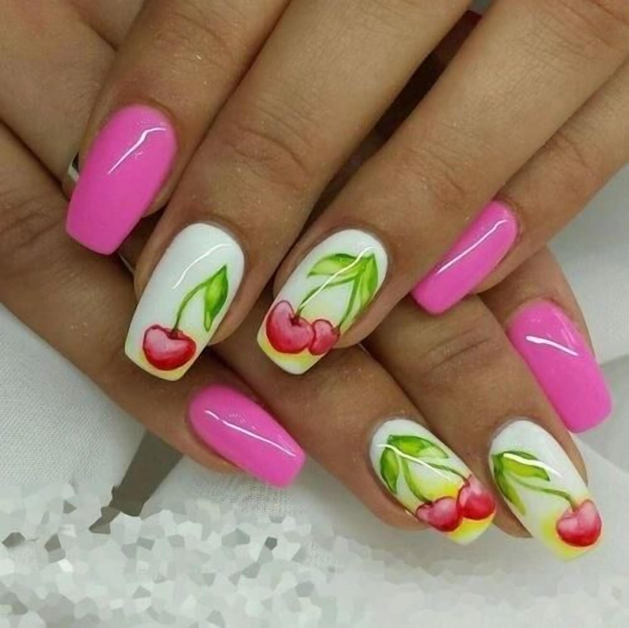 Ein Nahaufnahme einer Hand mit langen, rosafarbenen Nägeln, verziert mit einem Kirschdesign.