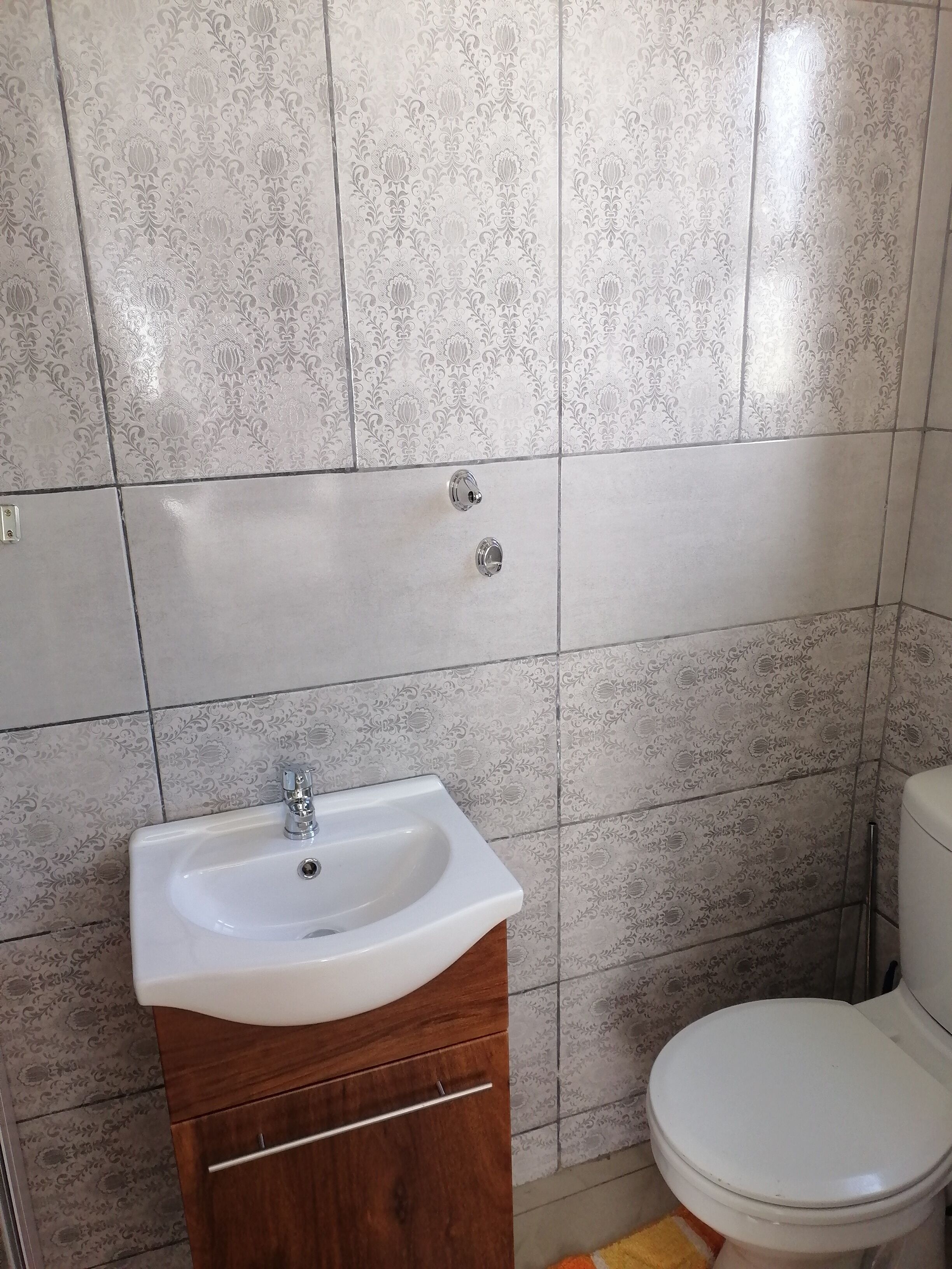 Une salle de bain avec un lavabo blanc, un meuble en bois et des toilettes.
