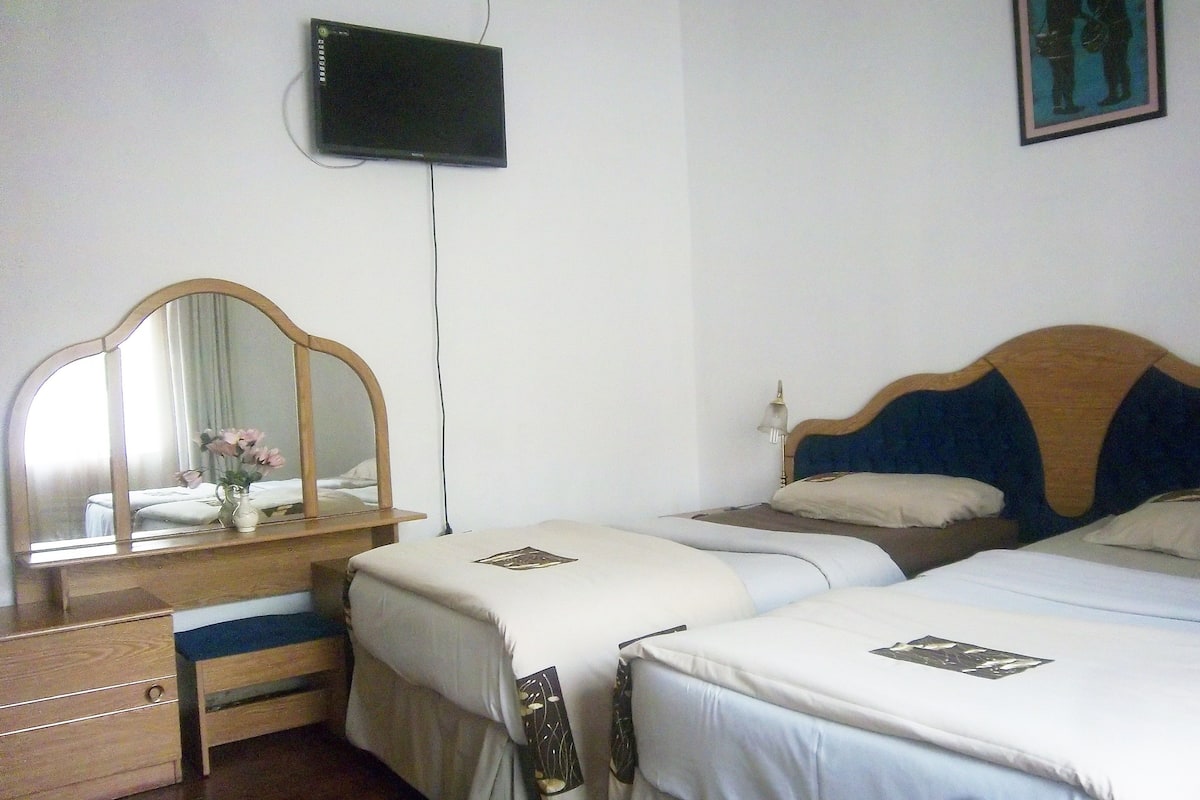 Habitación de hotel con dos camas, un aparador de madera, un espejo y un televisor en la pared.