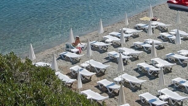 A beach with clear blue water, rocky cliffs, and sun loungers. - Litsa Mare apartments (Malevizi)