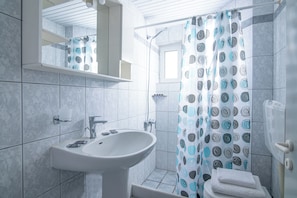 A bathroom with a sink, mirror, and shower curtain. - Litsa Mare apartments (Malevizi)