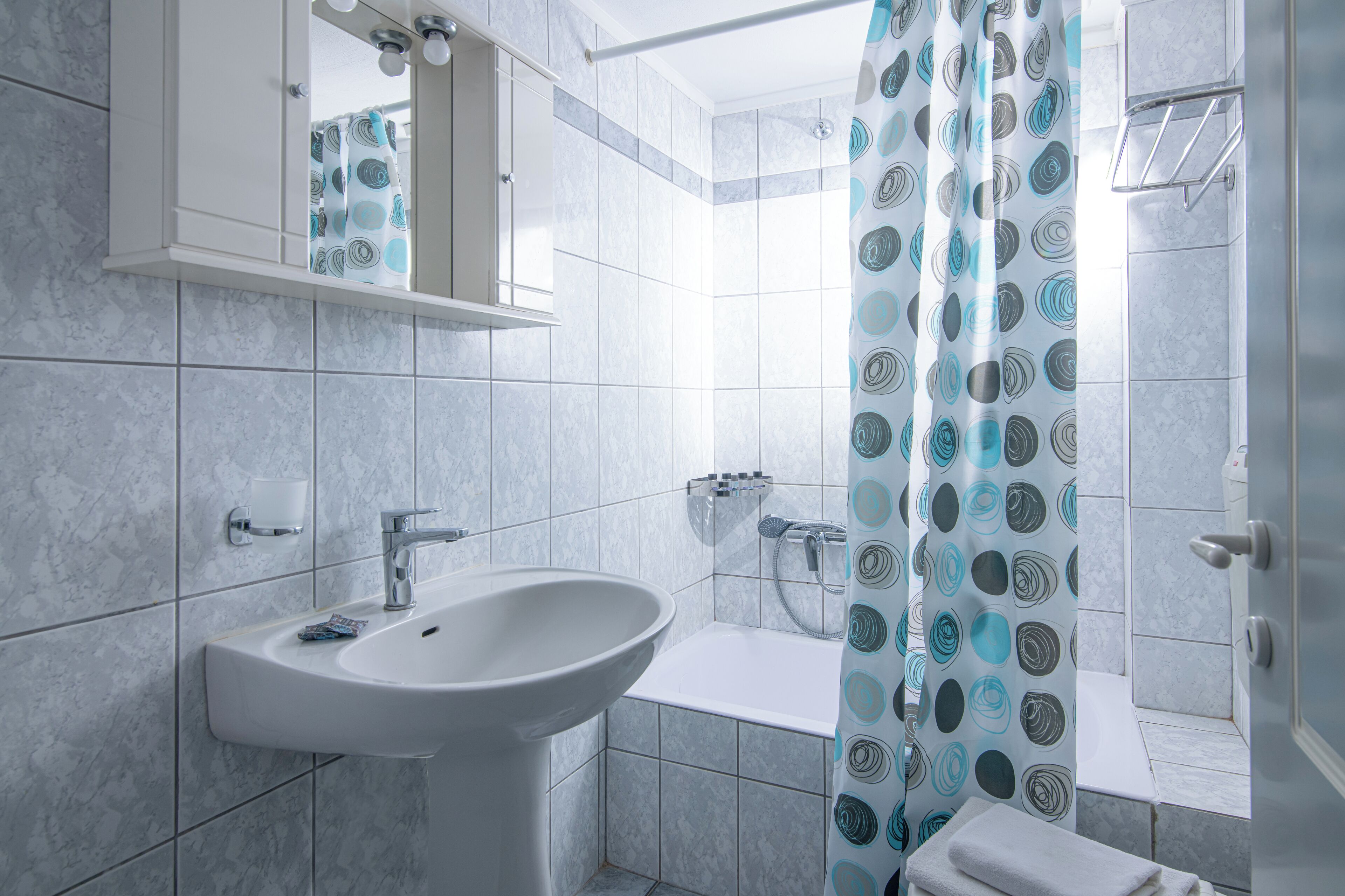 A bathroom with a sink, mirror, shower, and toilet.
