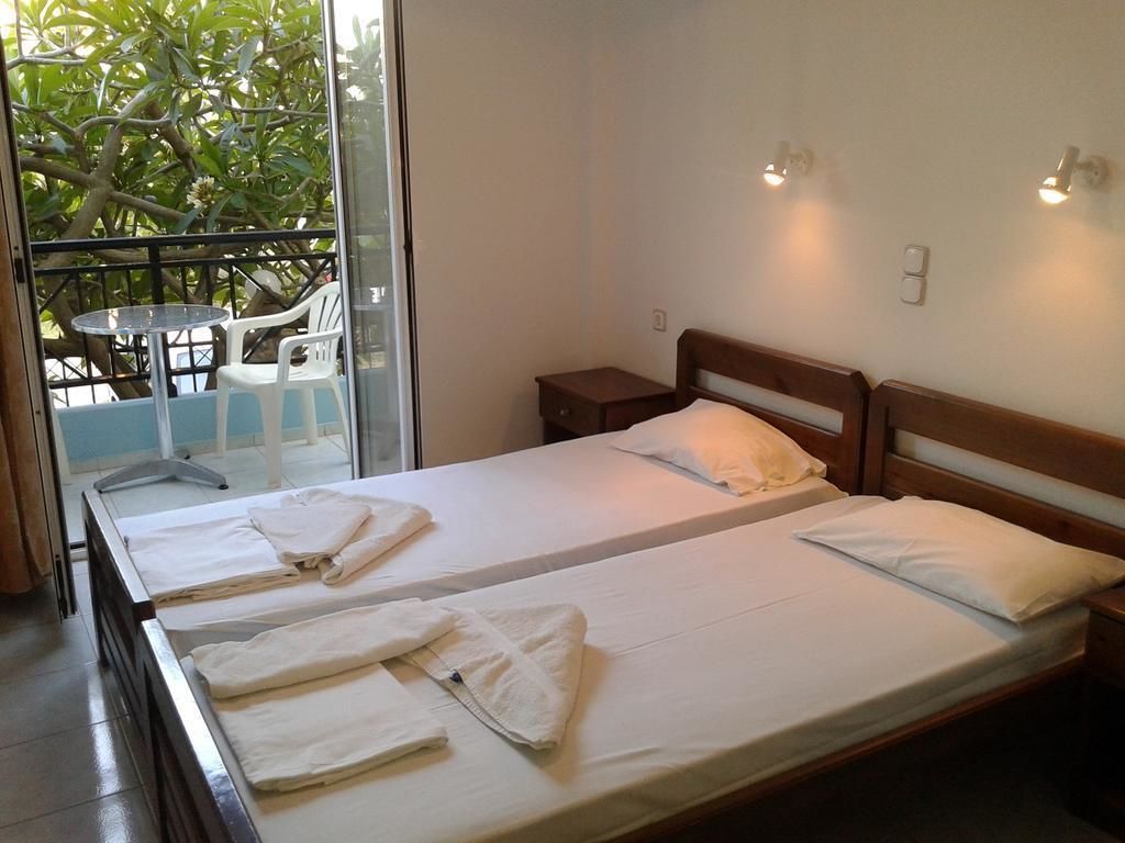 Ein Doppelzimmer mit zwei Betten und Sitzgelegenheiten vor einem Glastür.
