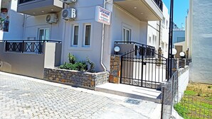 A multi-story building with balconies, air conditioning units, and a gated entrance. - Litsa Mare apartments (Malevizi)