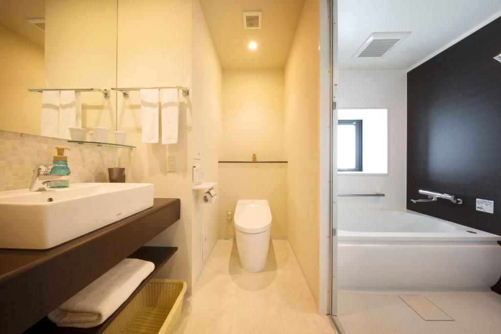 Un baño moderno con un lavamanos blanco, un espejo y una bañera.