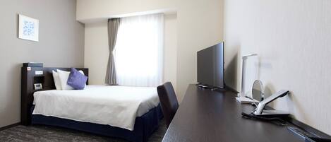 A hotel room with a bed, a desk, a television, and a window with curtains.