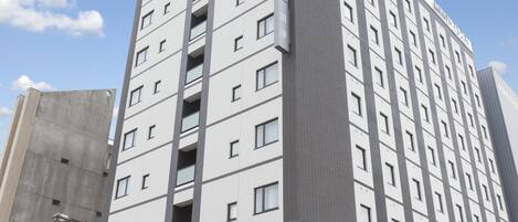 Un hotel moderno con varios pisos, un estacionamiento y cielo despejado.