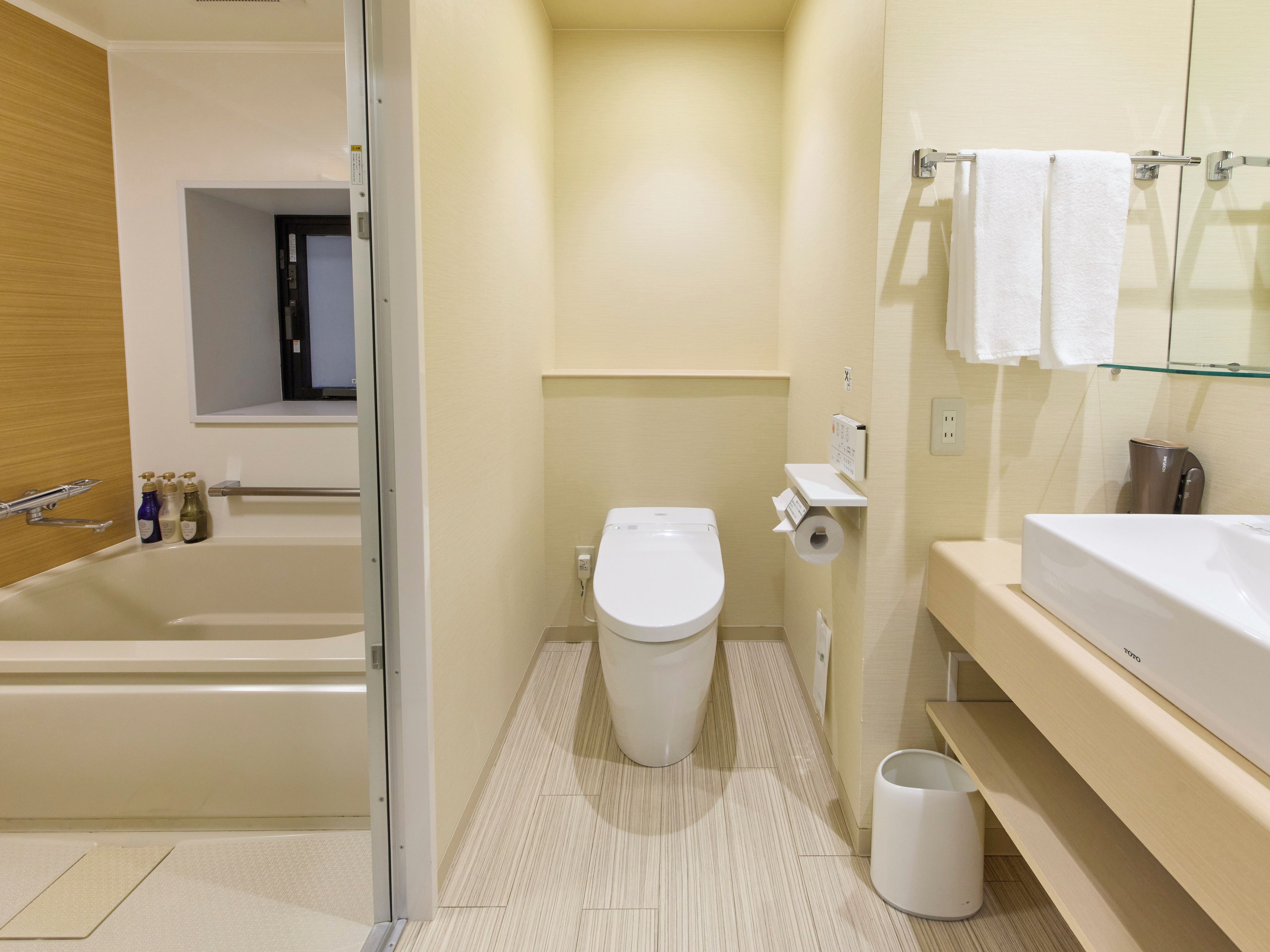 A modern bathroom with a bathtub, toilet, and a glass shower enclosure.