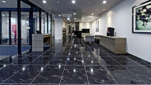 A modern hotel lobby with a black marble floor, glass partitions, a reception desk, and a seating area. - Shizutetsu Hotel Prezio Numazu (Numazu)