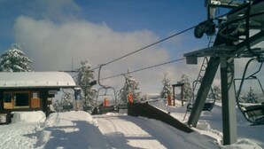 A ski lift with a wooden cabin and snow-covered trees in the background. - Gasthaus Falkenhain (Altenberg)