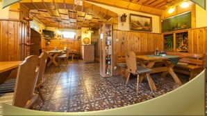 A rustic wooden interior with a dining area, wooden ceiling beams, and a tiled floor. - Gasthaus Falkenhain (Altenberg)