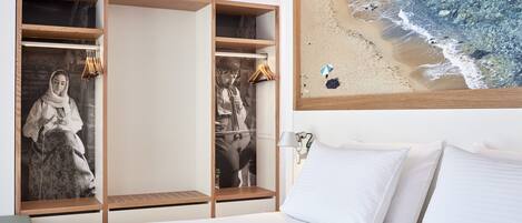 Habitación de hotel con cama, armario de madera con una obra de arte con temática playera, y vista a la playa.