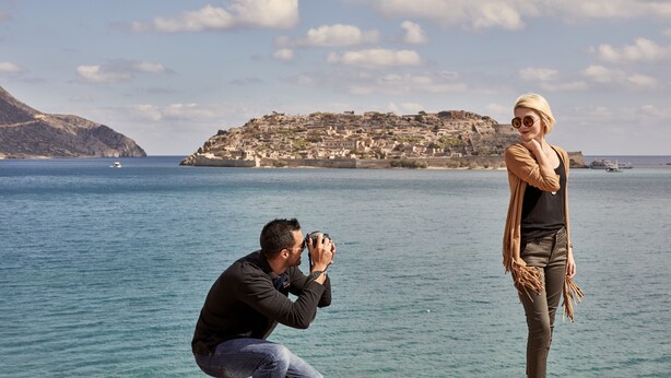 Une scène côtière où une personne prend une photo d’une autre personne qui se tient près de l’eau.