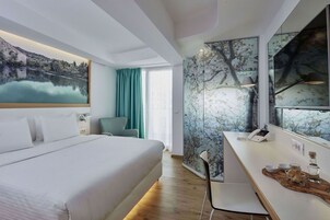 Quarto de hotel moderno com uma cama grande, uma escrivaninha com telefone e vista para um lago através da janela.
