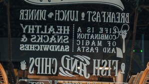 Deux personnes sont assises à une table, avec un menu affiché derrière elles.
