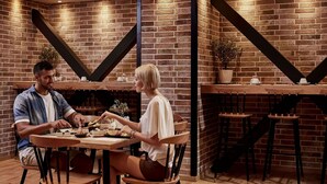 Un restaurant chaleureux avec des murs en briques, des tables en bois et des poutres en métal noir.