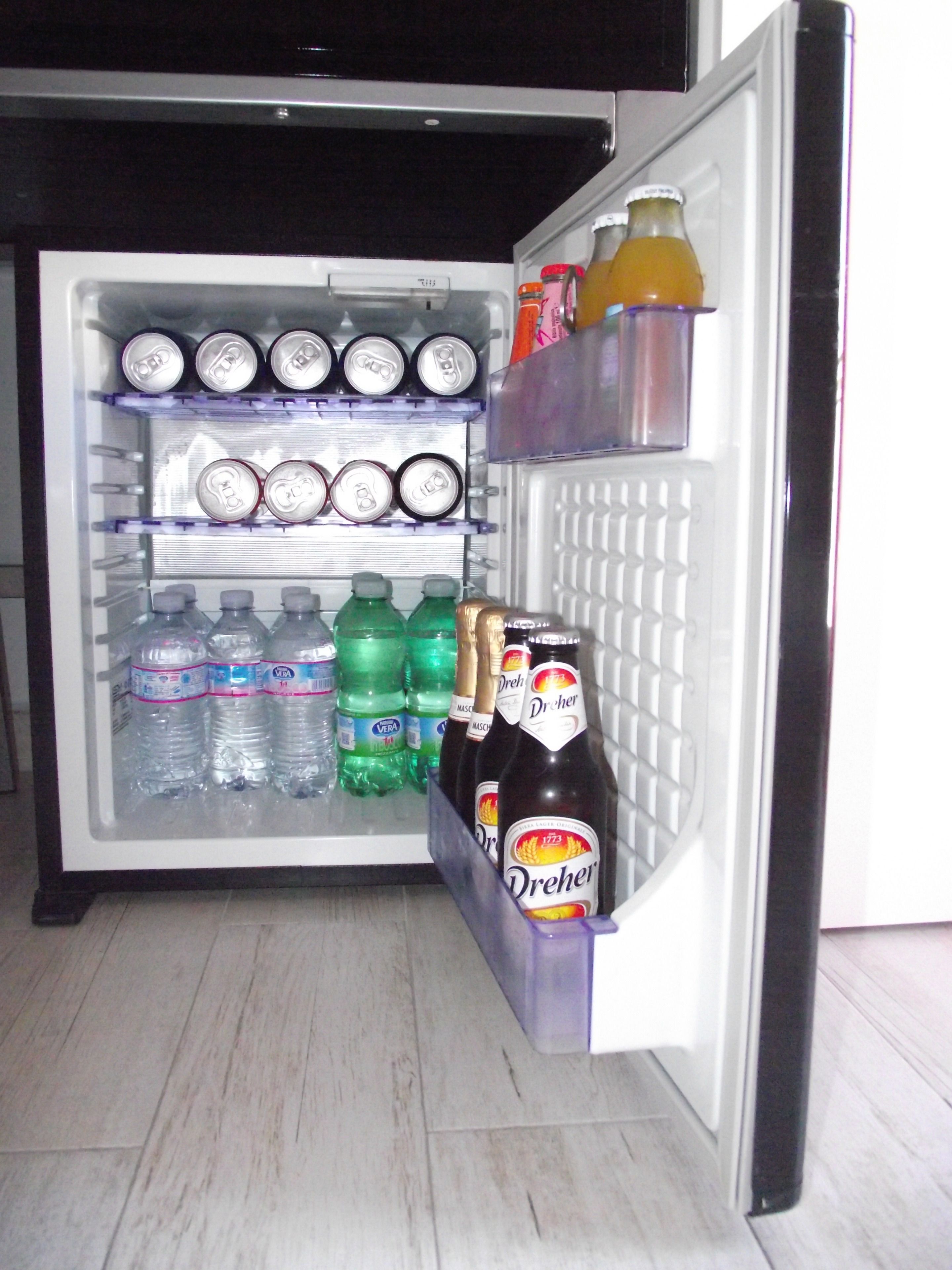 An open refrigerator stocked with various beverages including water, soda, and beer.