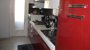 A kitchen with white cabinets, a red refrigerator, and a black countertop. - B&B Il Mare degli Dei (Letojanni)