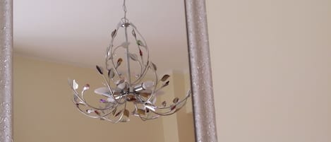 A mirror with a decorative metal frame and a hanging chandelier.